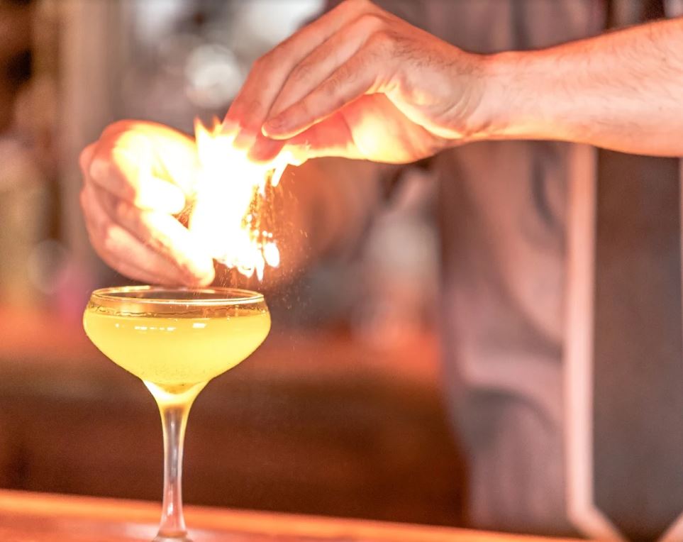 Cocktail with fire coming from bartenders hands